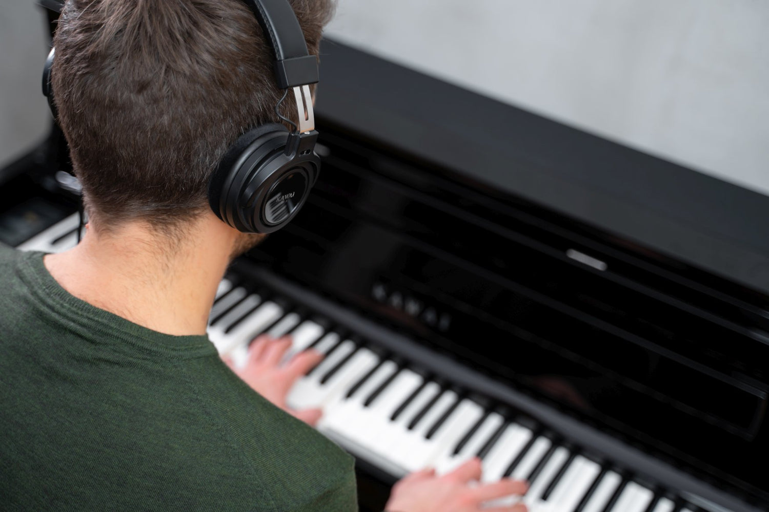 Man playing Kawai digital piano with headphones