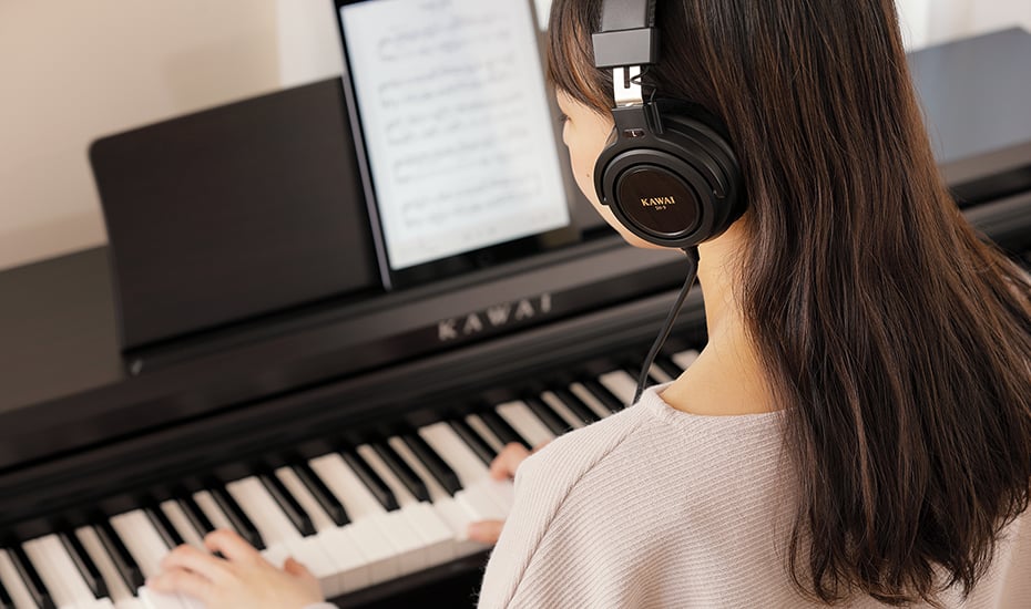 girl playing Kawai digital piano wearing heapdhones